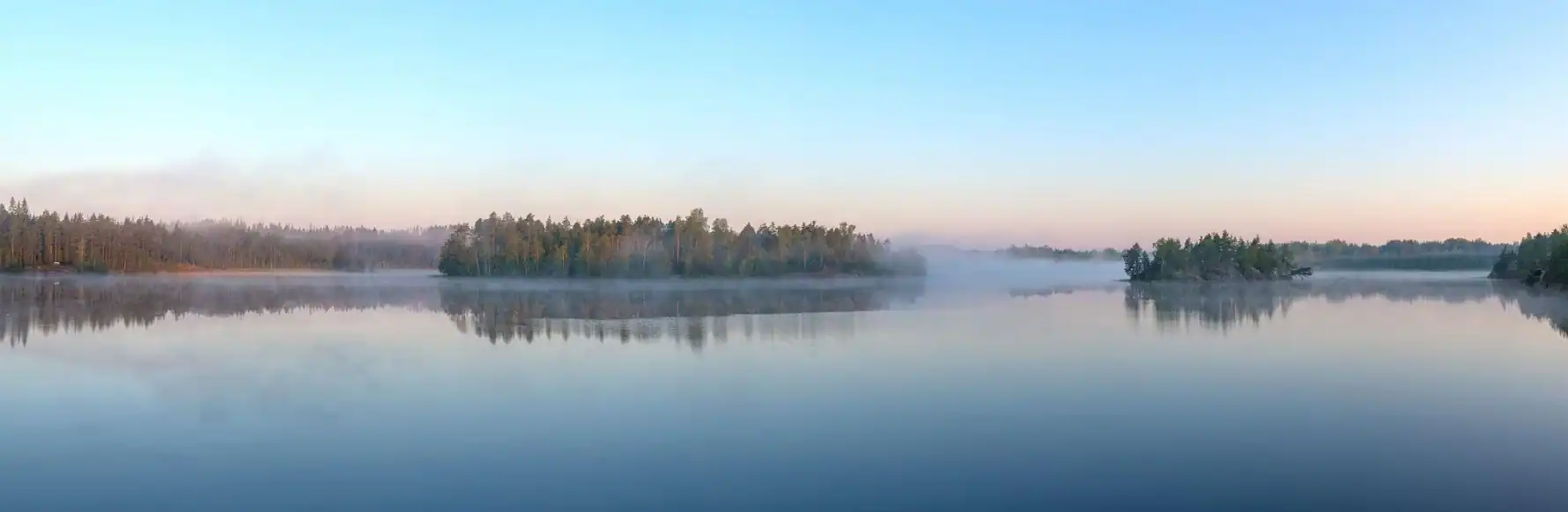 Lac calme au lever du jour, reflets et brume